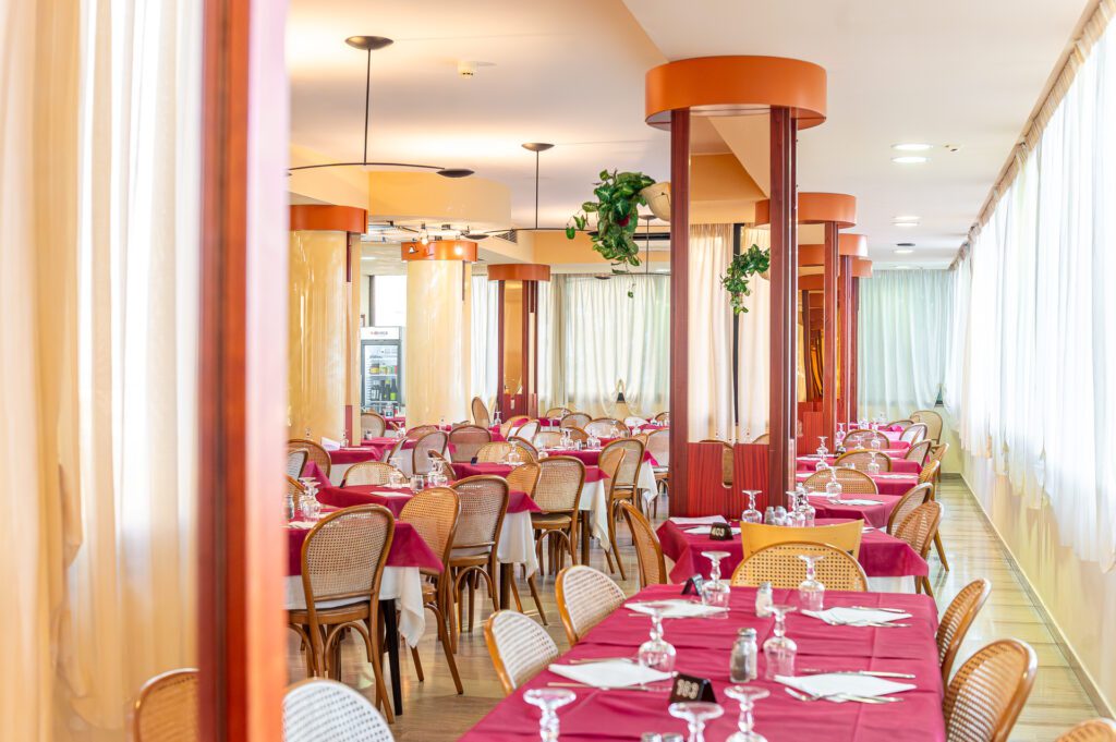 Ristorante elegante con tavoli apparecchiati e sedie in legno intrecciato.