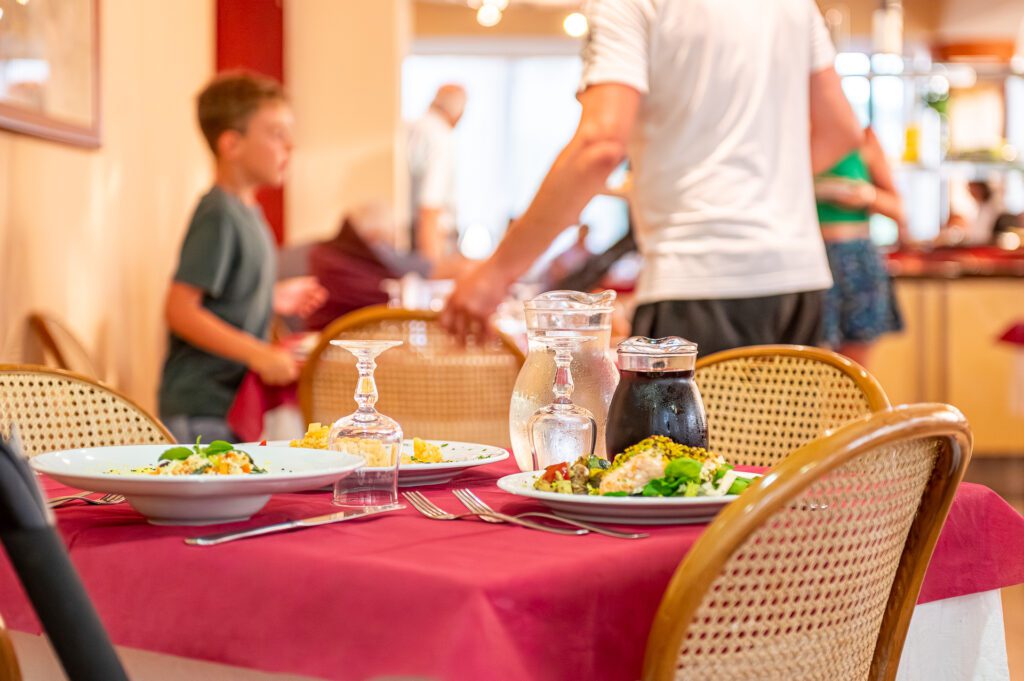 Tavola imbandita con cibi e bevande in un ristorante affollato.