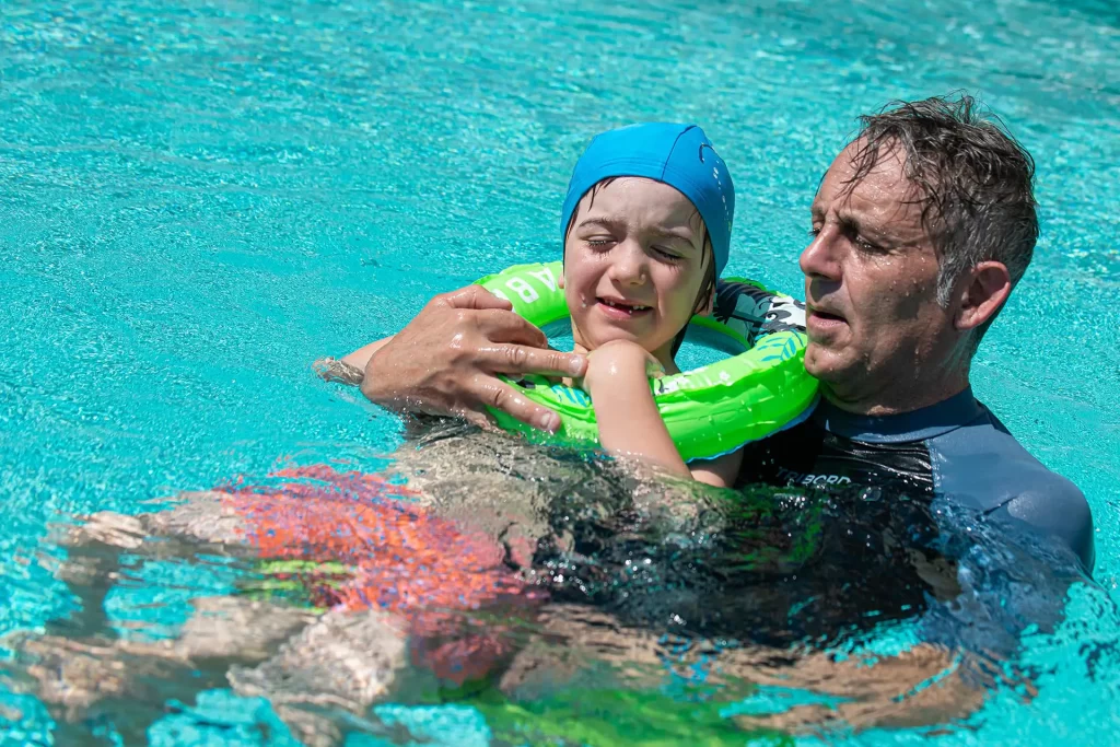 Un istruttore aiuta un bambino con un salvagente in piscina.