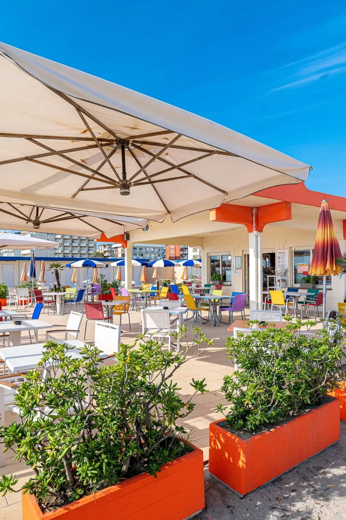 Terrazza estiva con sedie colorate e ombrelloni in riva al mare.