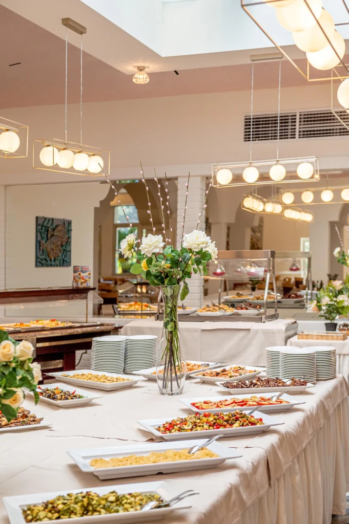 Tavolo da buffet elegantemente allestito con piatti variopinti e decorazioni floreali.