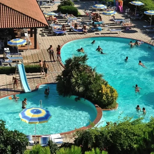 Persone che si rilassano e nuotano in una piscina all'aperto in una giornata di sole.