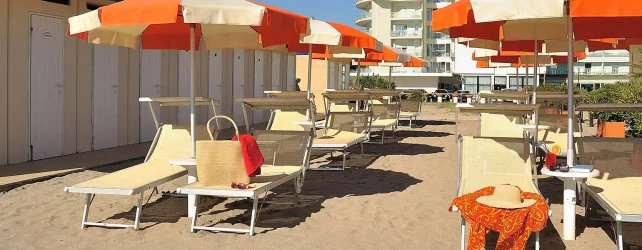 Spiaggia con lettini e ombrelloni arancioni.