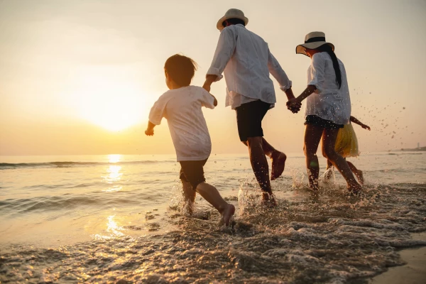 Famiglia che cammina sulla spiaggia al tramonto, godendo della brezza marina.